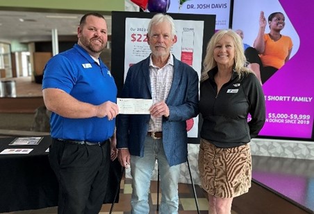 Three people gathered for photo with donation check