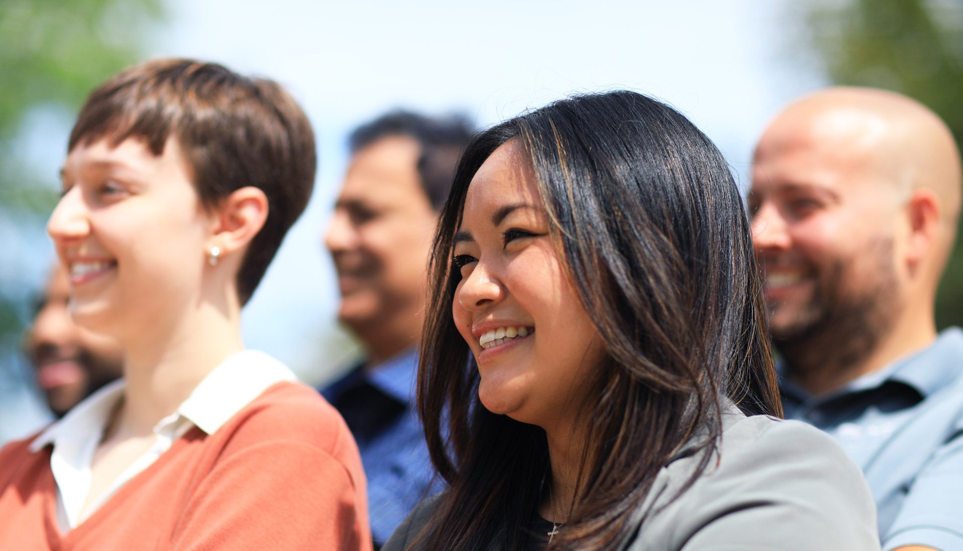 Five people looking off in the distance outside with smiles