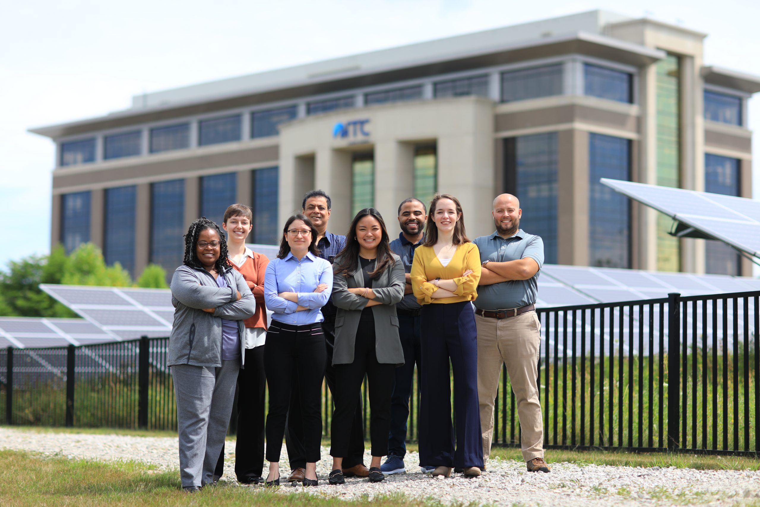 Group of eight people in front of ITC headquarters in Novi, Michigan smiling with arms crossed.