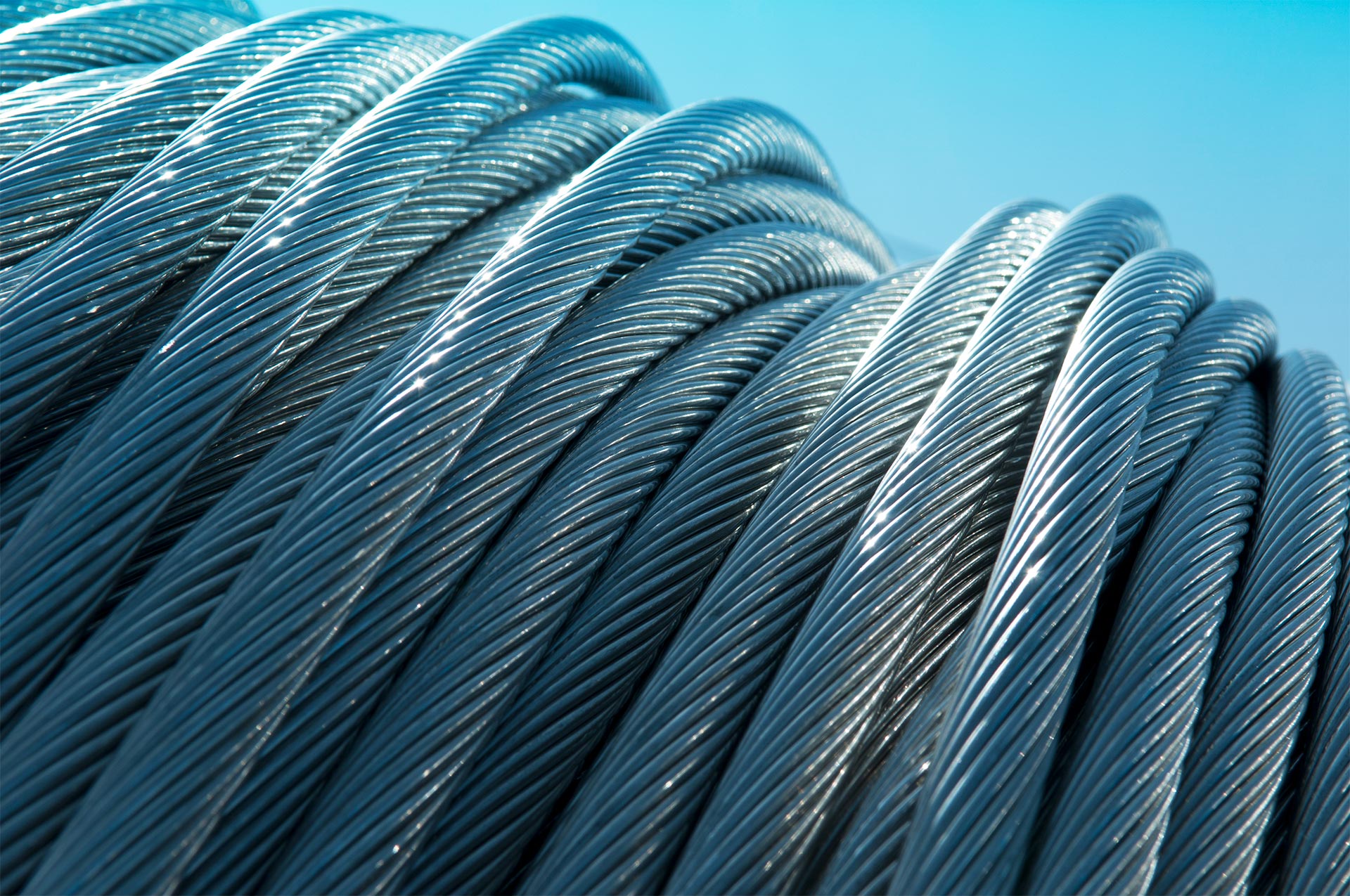 Close up of transmission power lines (coiled) in front of light blue background