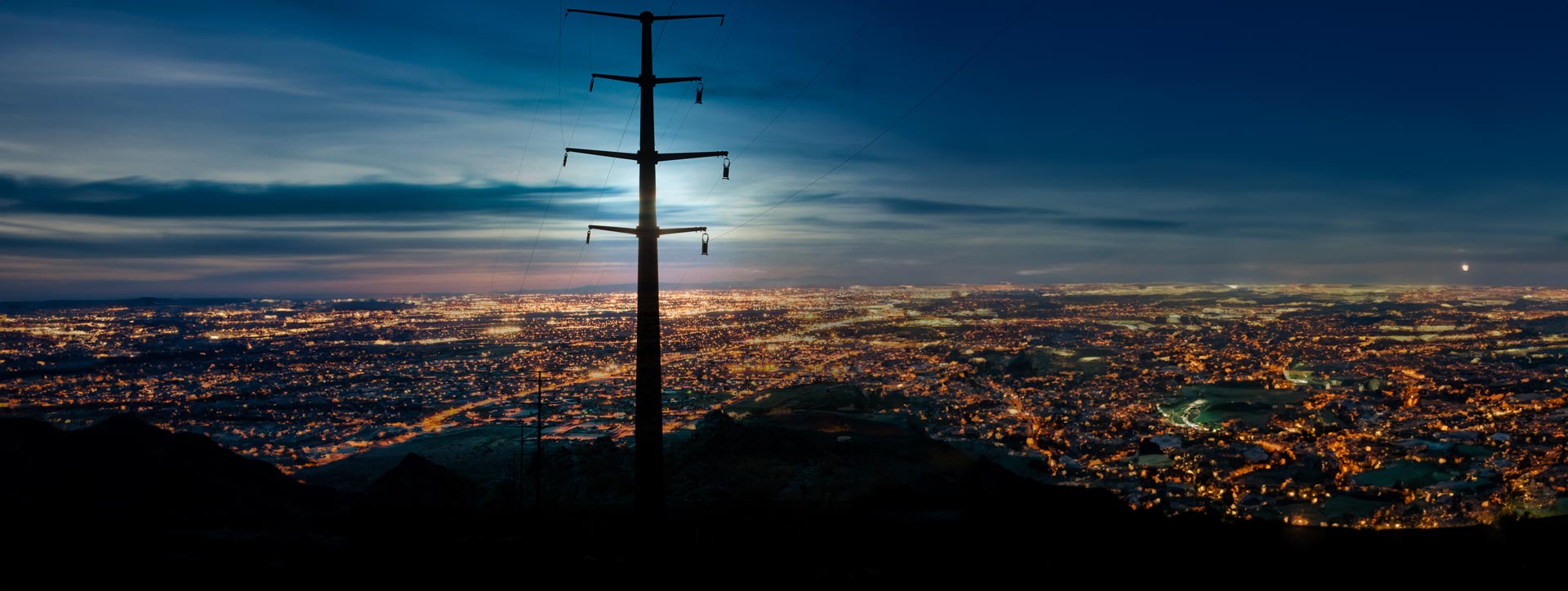 Nightscape of rural city with transmission line in foreground.