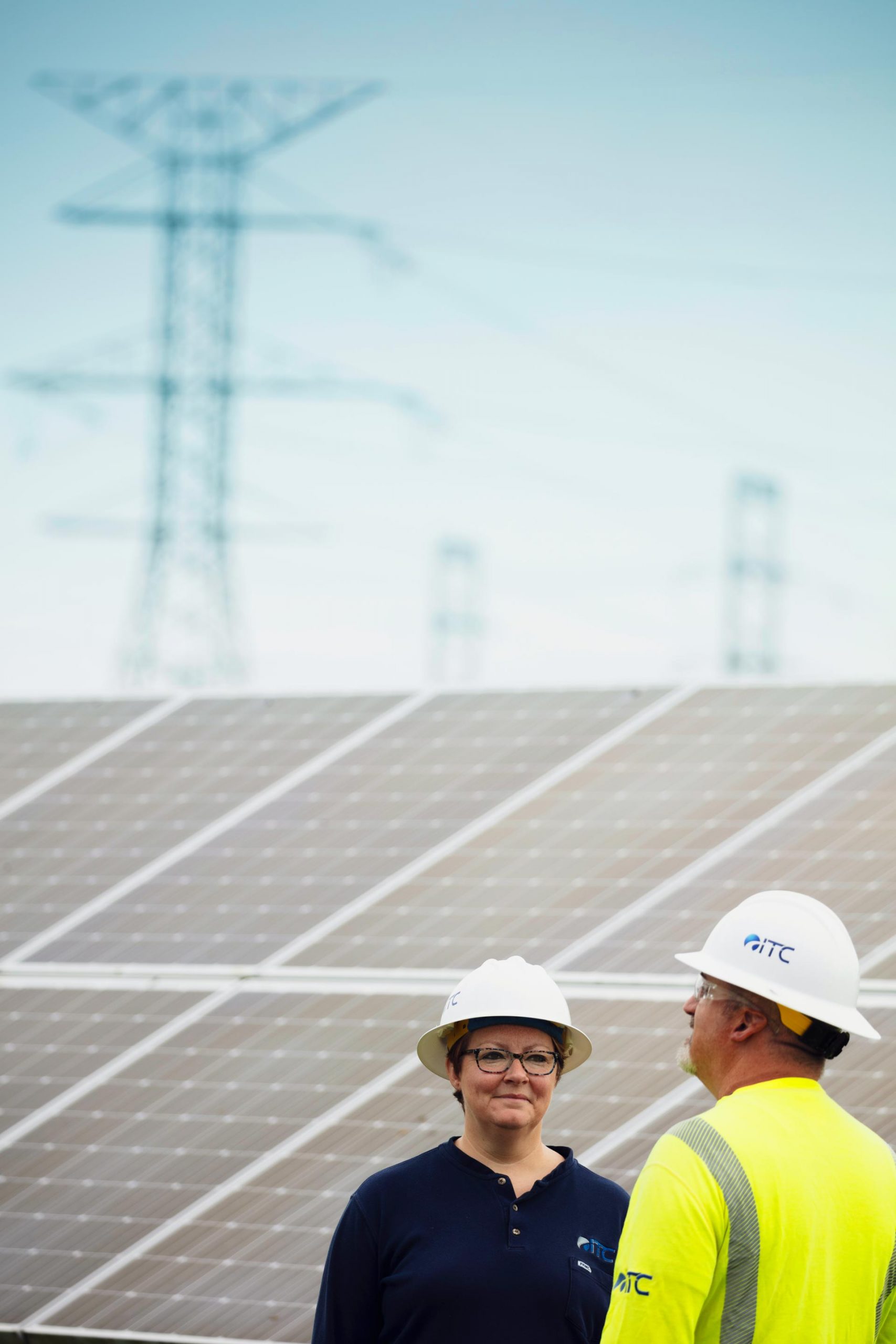 ITC Employees in front of Solar Panels and Transmission Lines