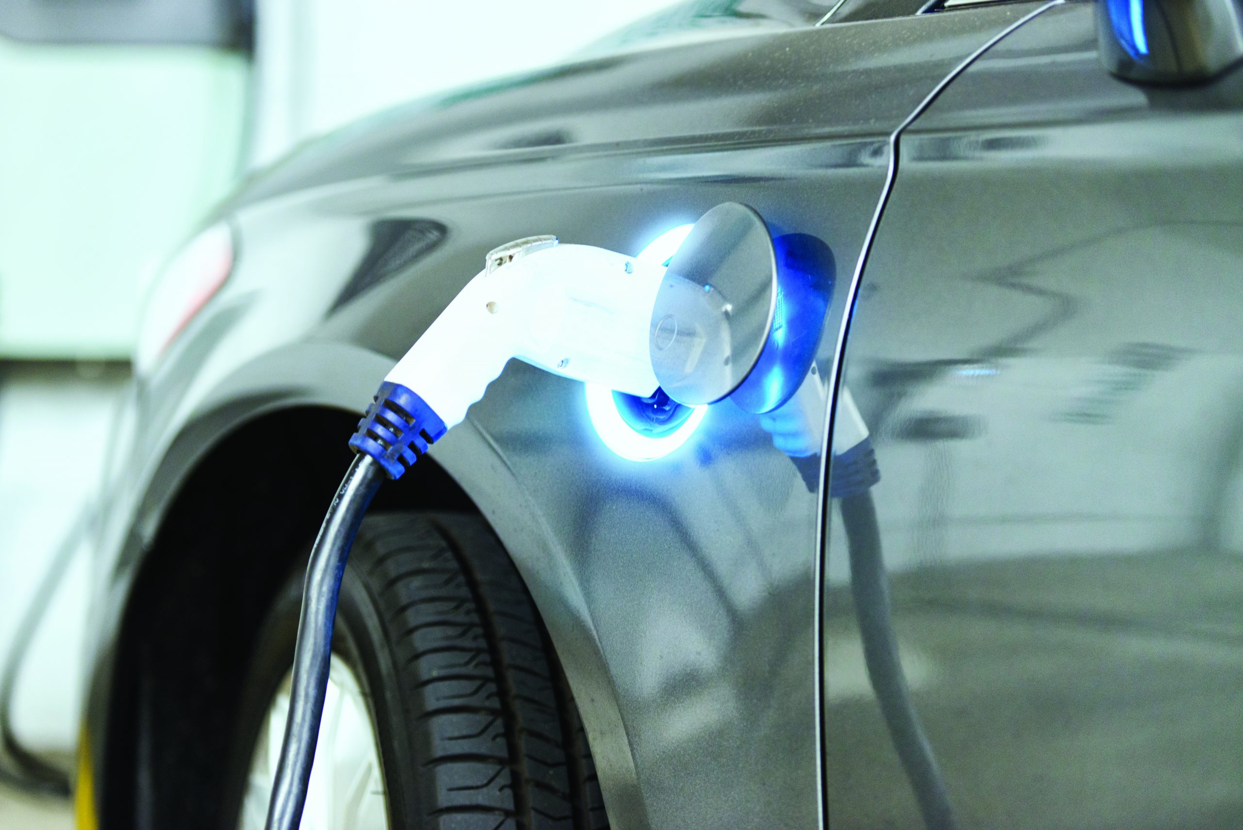 Power supply plugging into gray electric vehicle.