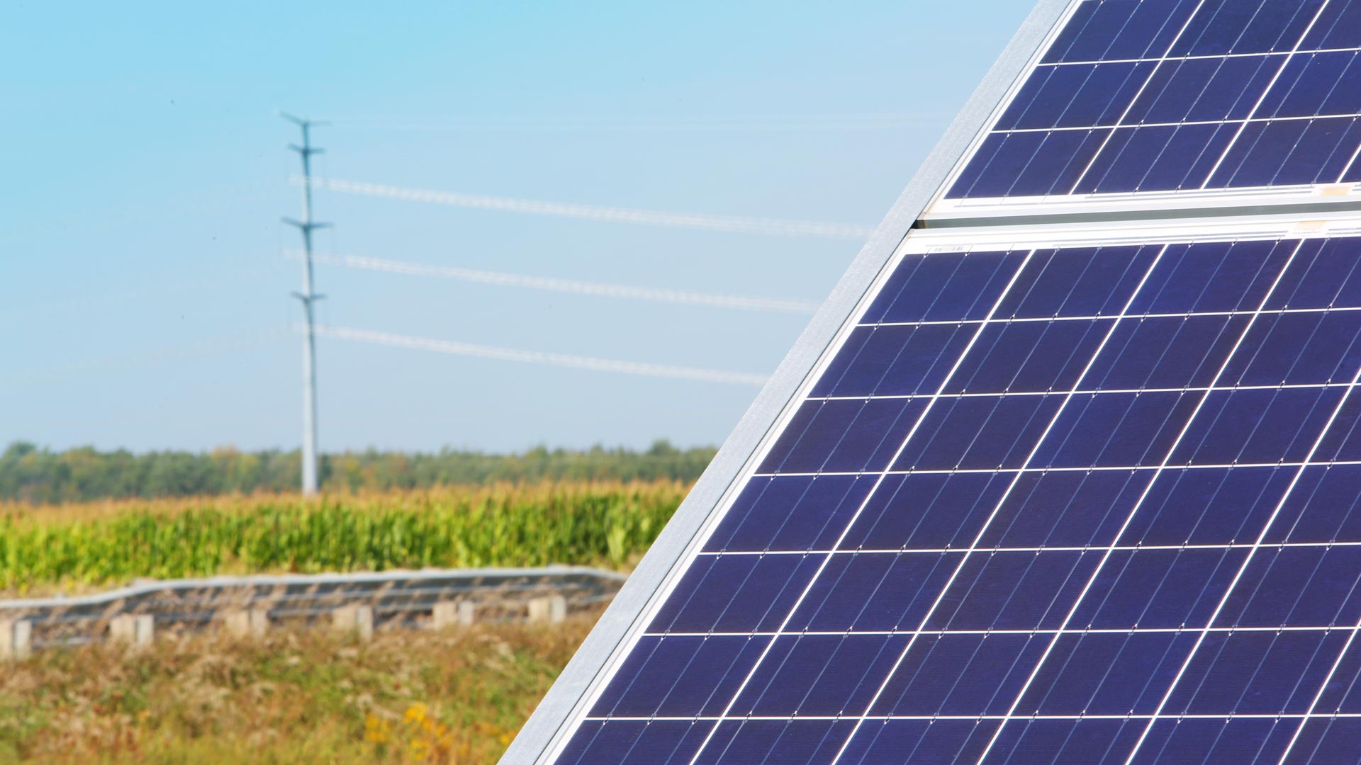 Solar pannel in field with electric monopole in distance.
