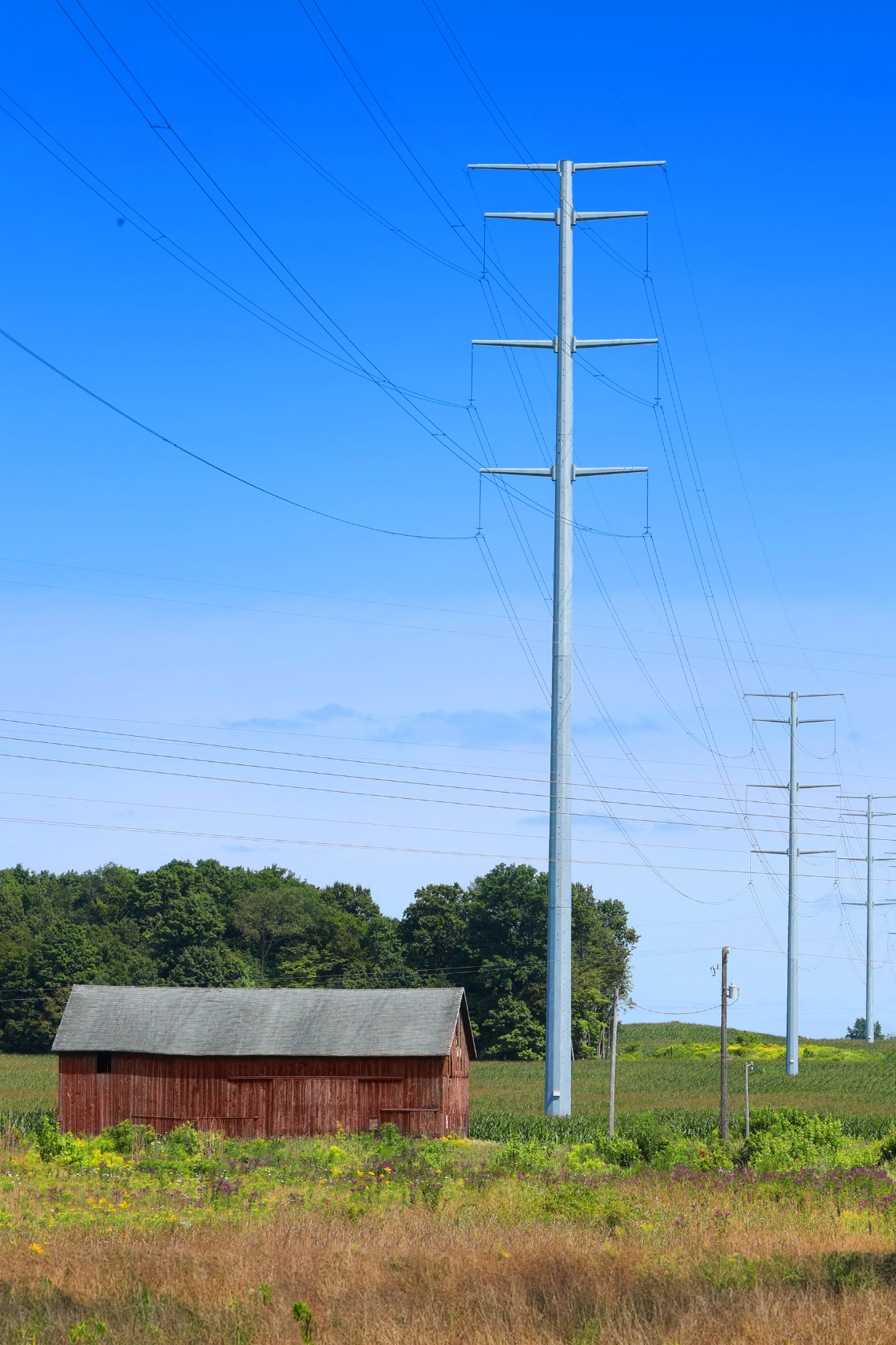 Transmission corridor alongside red barn.