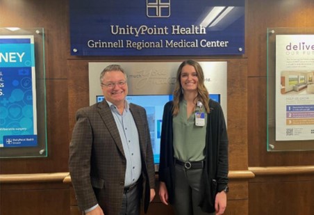 Two people standing below Unity Point Health sign in medical center building.