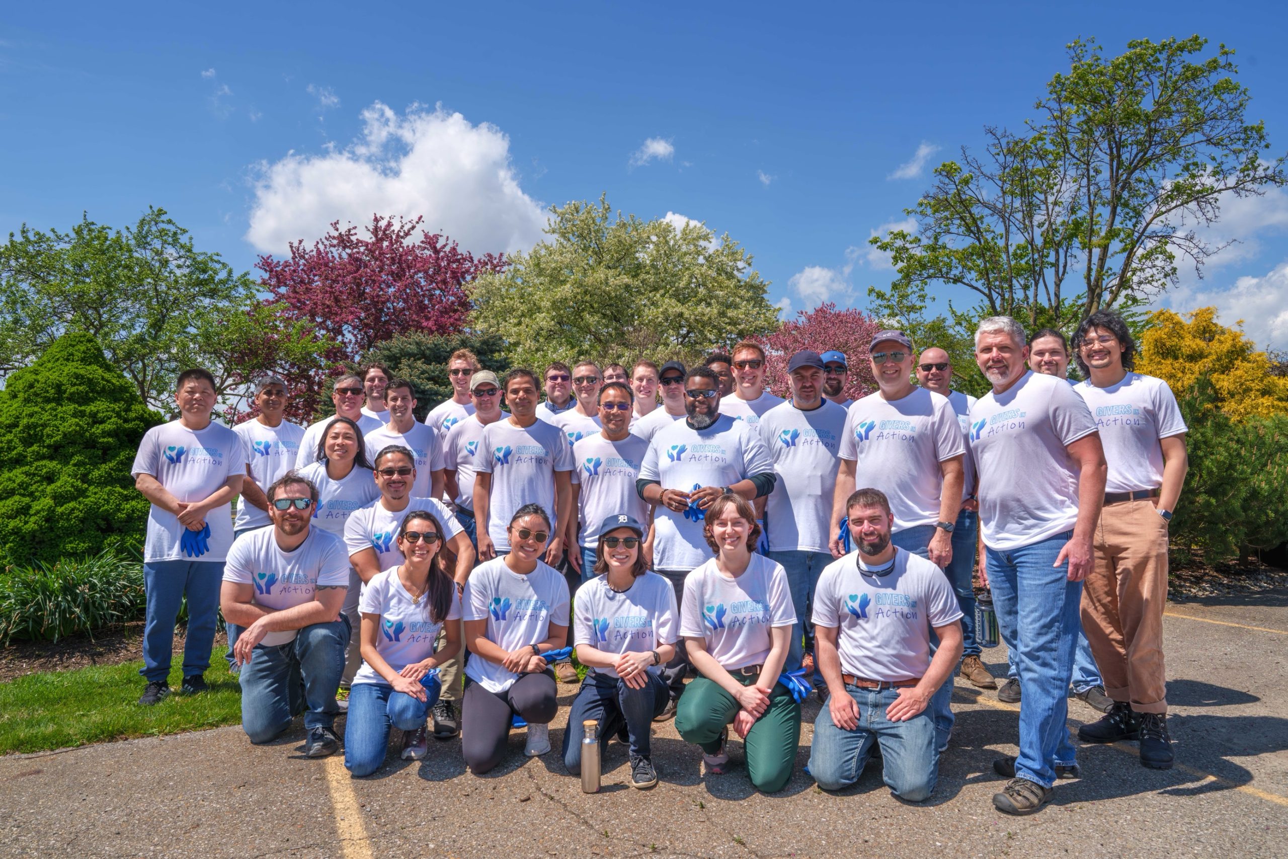 Large group of volunteers posed in front of colorful landscape.