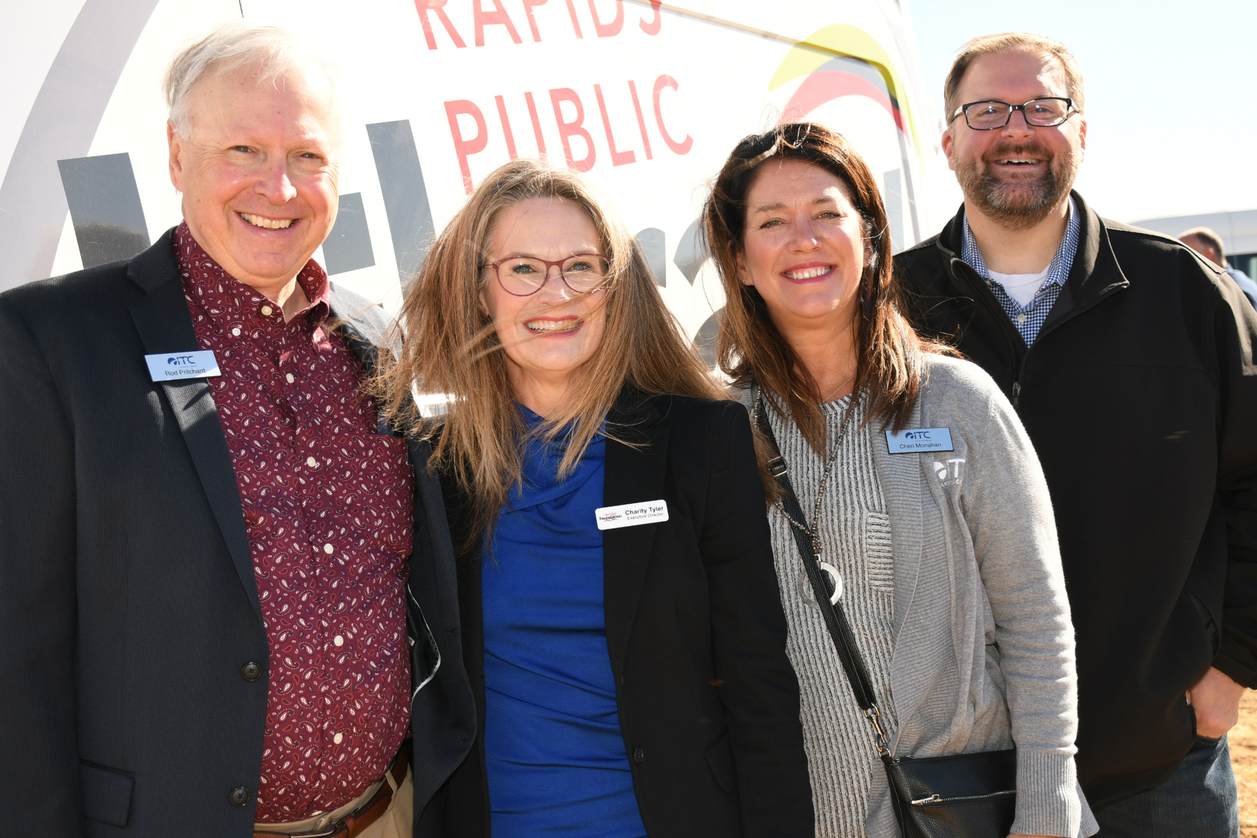 Group of four people posed for a picture in front of cedar rapids public library truck.