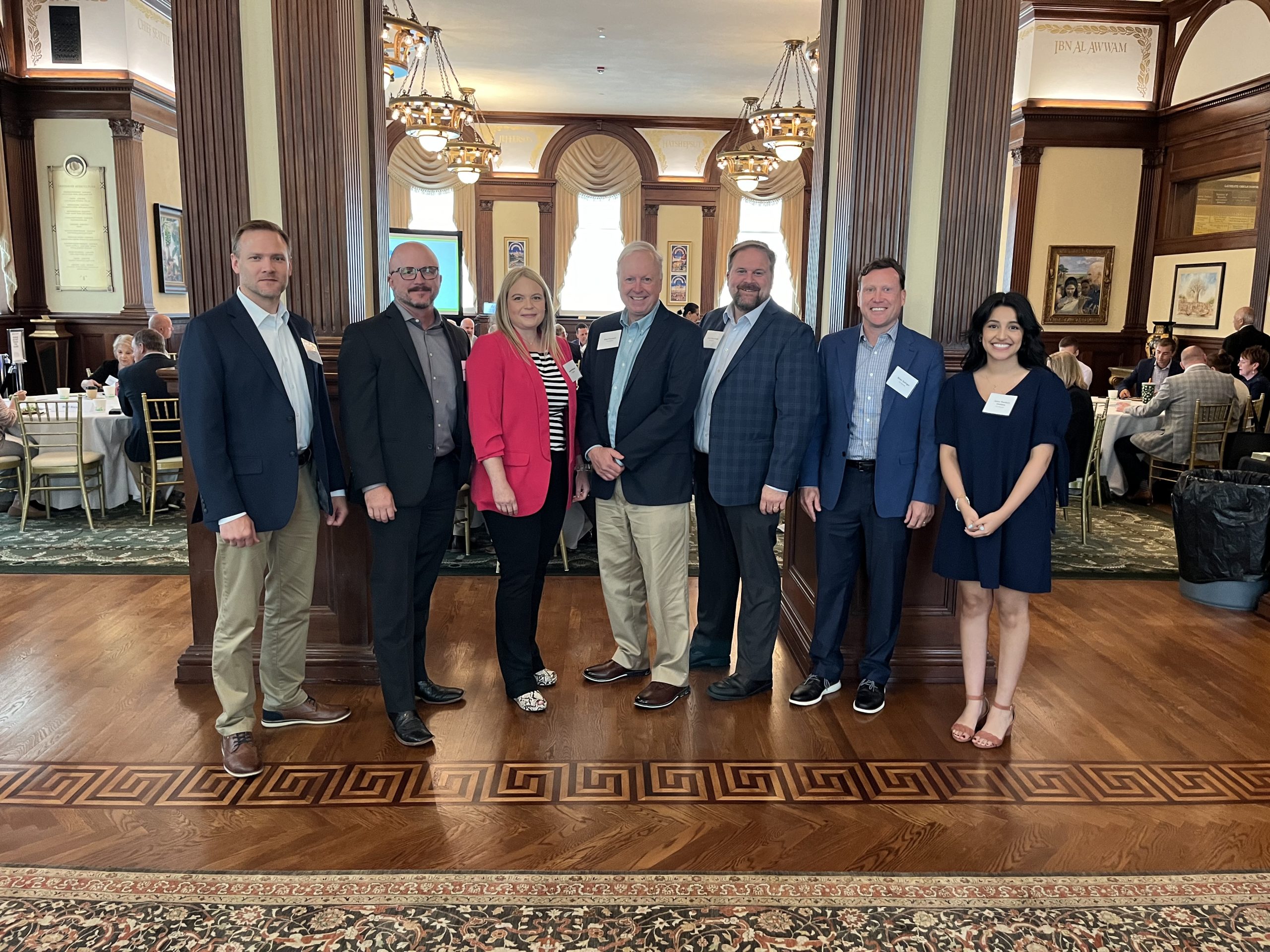 Group of seven people posed for a picture in front of a banquet.
