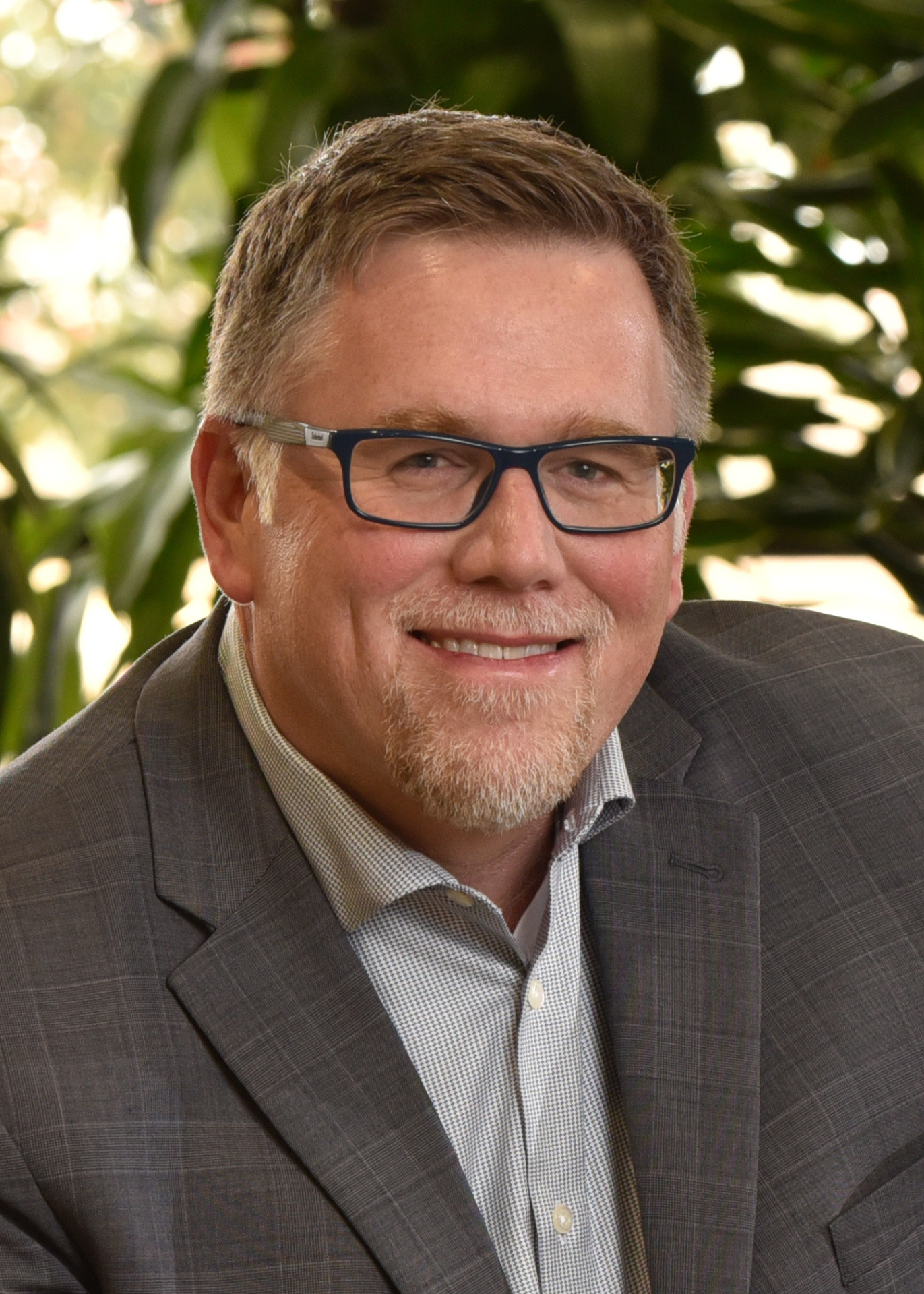 Headshot of Tim Greenen on greenery background.