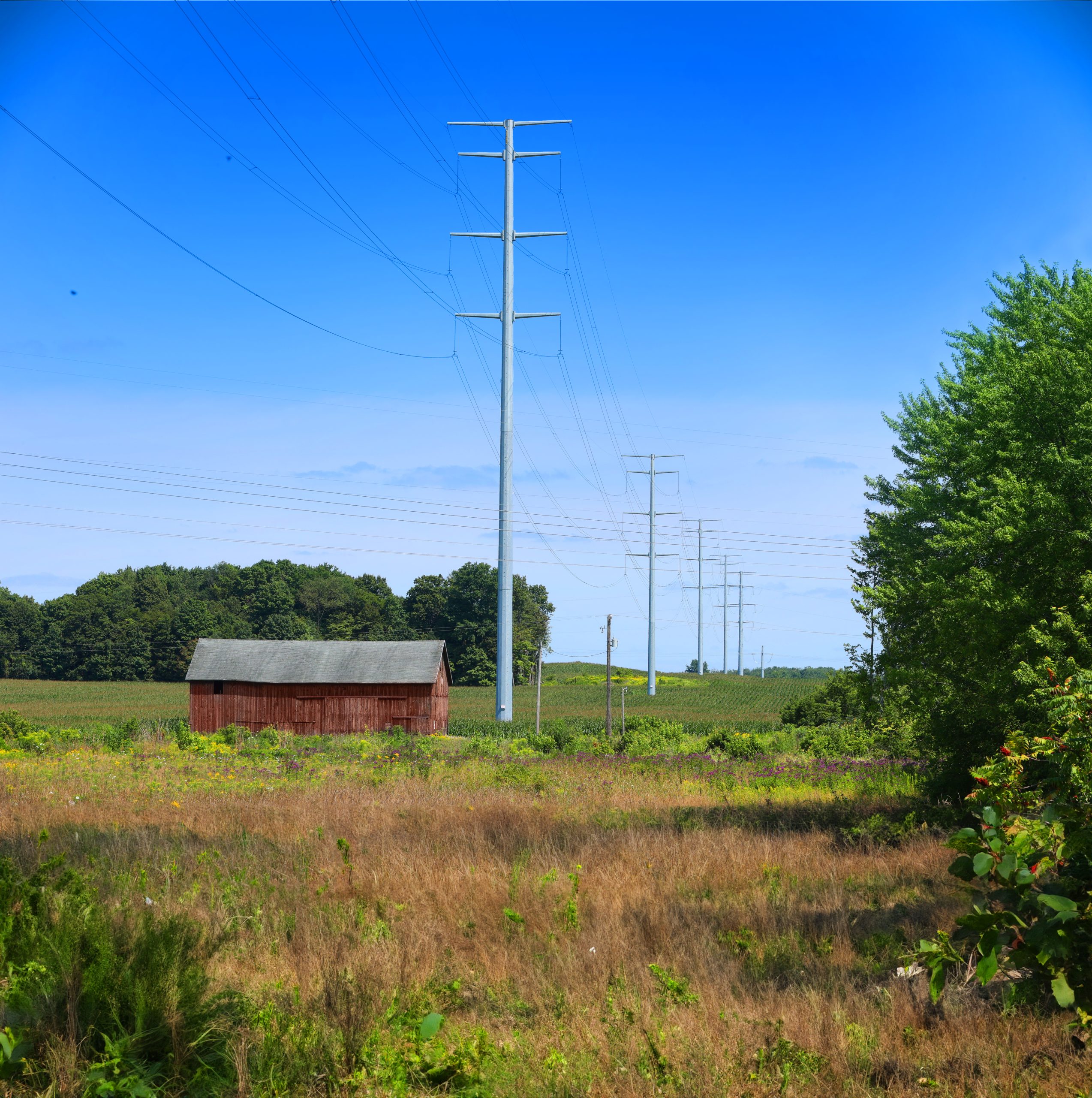 Transmission corridor alongside red barn.