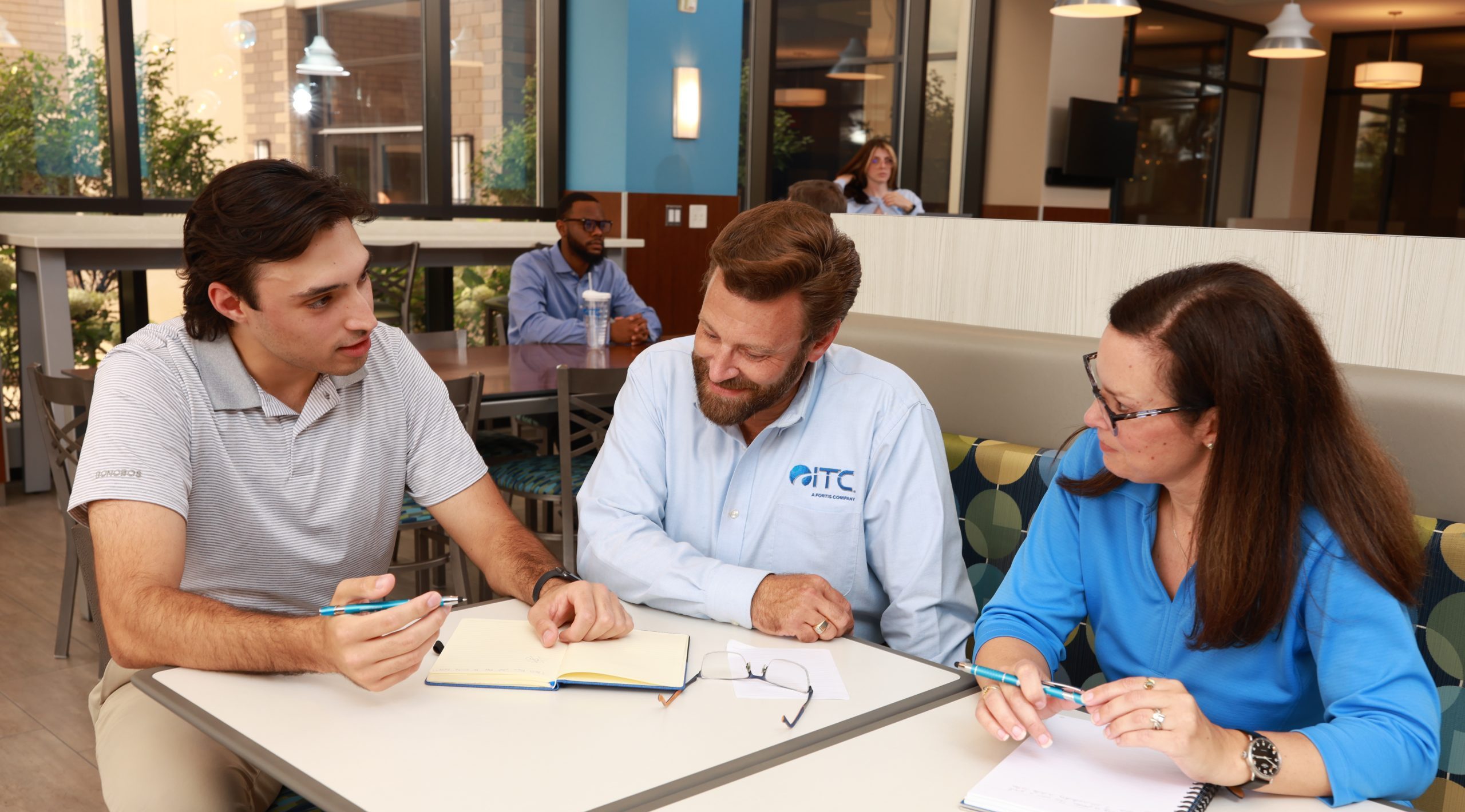 Three employees chatting in ITC cafe.