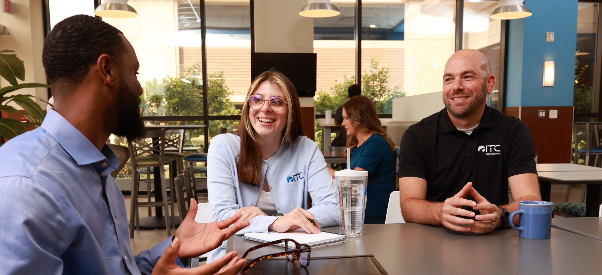Group of three employees chatting in ITC headquarters cafe.
