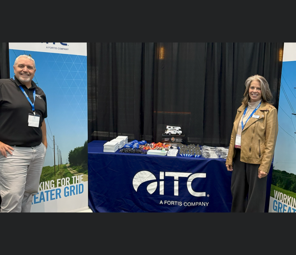 Two people standing beside ITC table at community event.