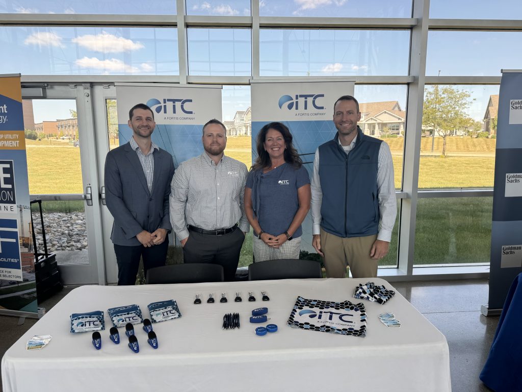 Four people in front of ITC banners at a company event.